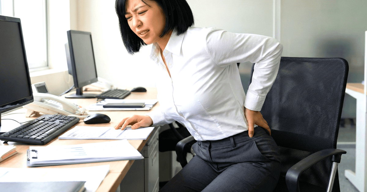 椅子から立ち上がる時に坐骨神経痛で痛がる女性